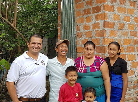 Photo of Salvadoran family with a pastor by a latrine