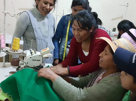Photo of Bolivian women gathered around a sewing machine
