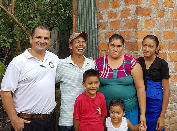 Photo of Salvadoran family with a pastor by a latrine