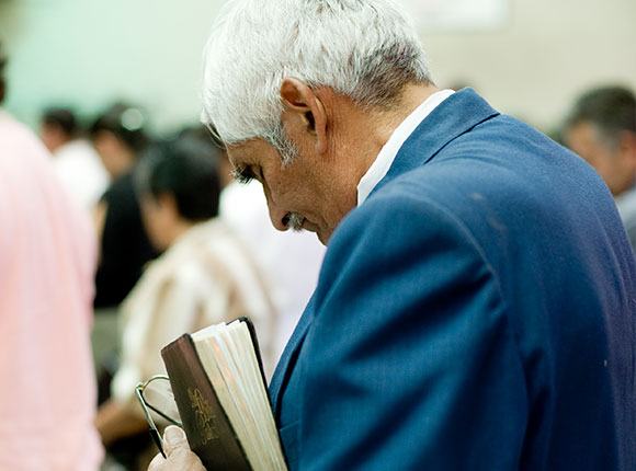 Photo of elderly man at church holding a Bible