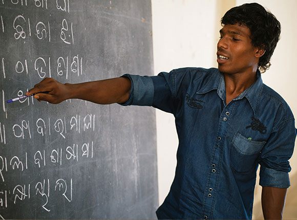 Photo of Indian man pointing at a chalkboard