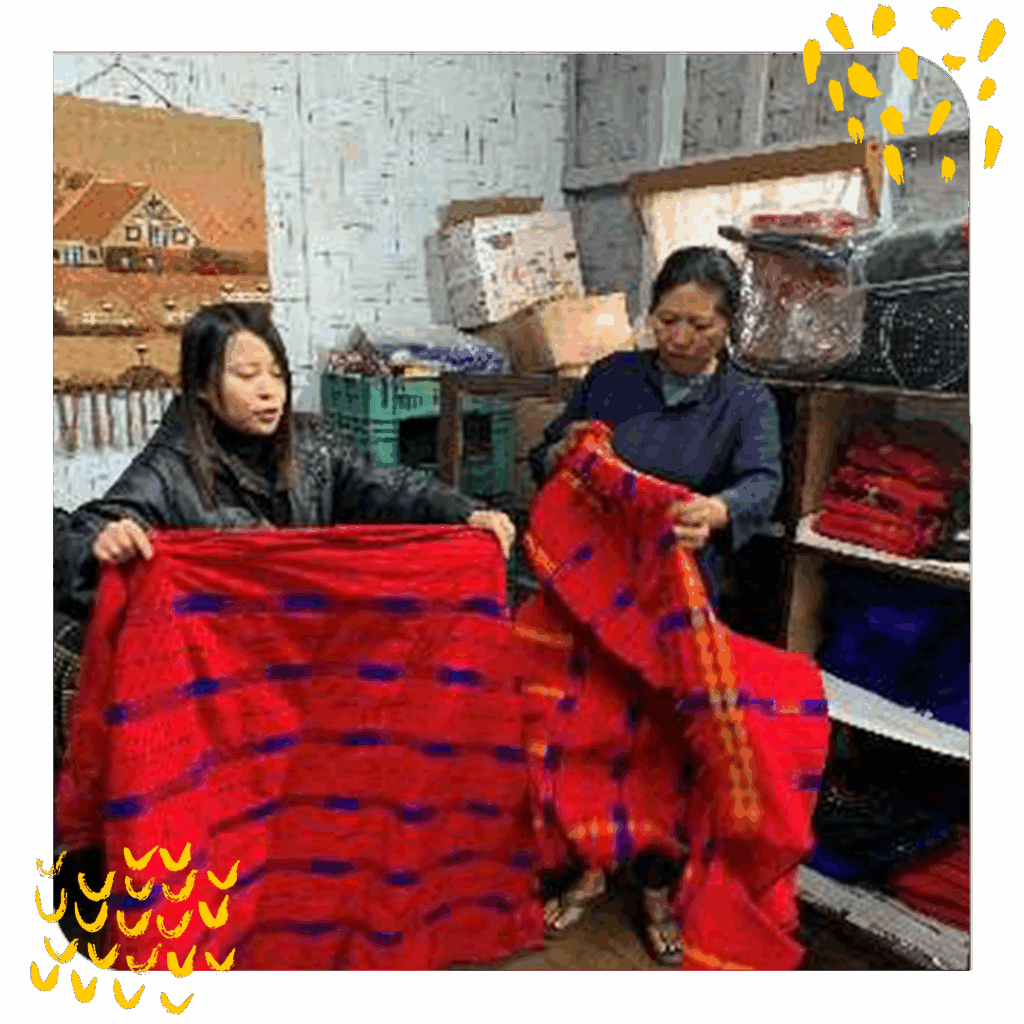 Two women hold a red blanket. Photo depicts women's employment initiatives